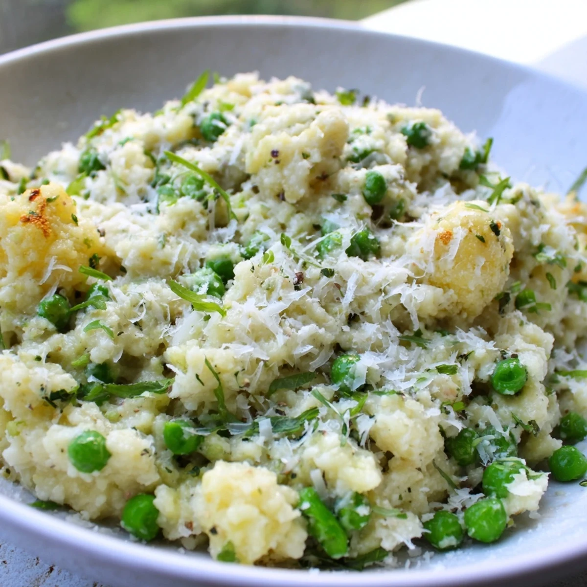A creamy bowl of Creamy Parmesan Orzo with Green Peas, topped with fresh parsley.