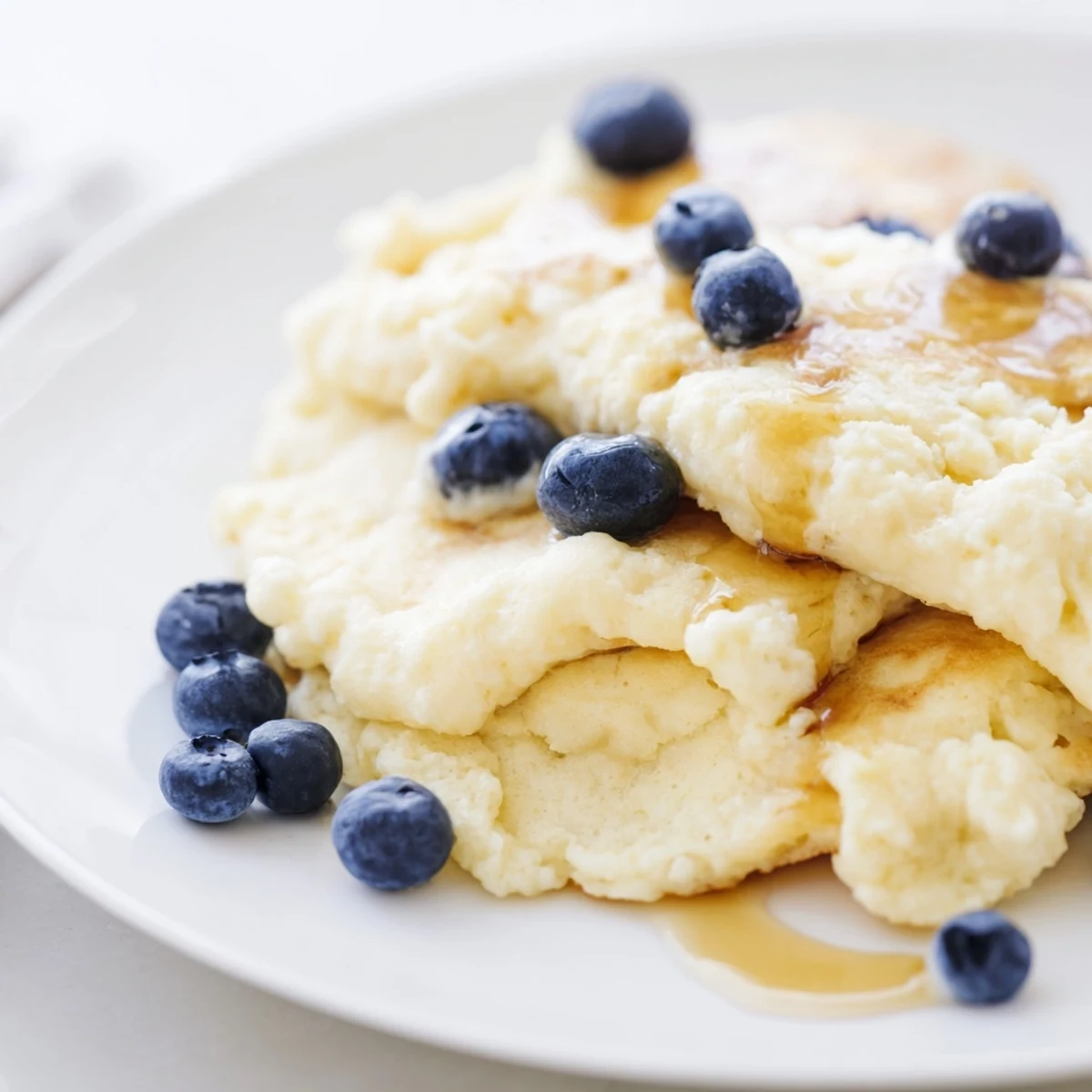 Warm, appetizing photo of soft, tender, fluffy scrambled pancakes, ideal for dipping in maple syrup.