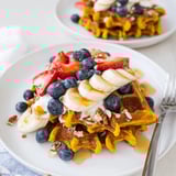 Hearty Anti-Inflammatory Adaptogenic Turmeric Waffles topped with yogurt, fresh berries, and a drizzle of honey.