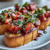 Fresh strawberry bruschetta with balsamic and mint on toasted baguette slices, drizzled with sweet-tangy glaze. Ideal for summer entertaining or light appetizers.