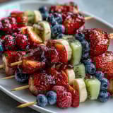 Festive Fourth of July fruit skewers with strawberries, bananas, and blueberries in patriotic red, white, and blue layers.