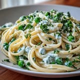 Spring pasta delight: lemony ricotta linguine with tender peas, garnished with parsley and Parmesan for a fresh vegetarian main.  