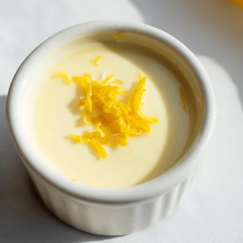 A close-up of a creamy 3-Ingredient Lemon Posset, ready to be served in elegant glass ramekins.