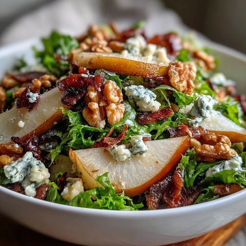 Frisée Pear Blue Cheese Bowl topped with crispy prosciutto and toasted walnuts, glistening with zesty vinaigrette.