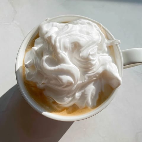 Golden espresso and lavender syrup swirl in a glass mug with steam rising from the frothy milk.  