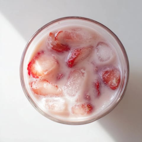 Chilled Refresher Copycat Pink Drink with strawberry syrup, coconut milk, and ice, garnished with fresh berries for a tropical sip.  