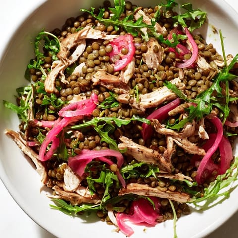 A close-up of the colorful Lentil & Chicken Spring Salad highlights tender lentils, shredded chicken, peppery greens, and bright cherry tomatoes, ideal for a quick, high-protein lunch.  
