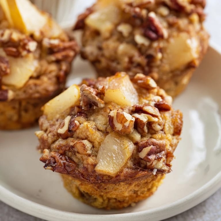 Close-up of fluffy Seasonal Spiced Pear and Walnut Muffins with visible pear chunks and walnuts.