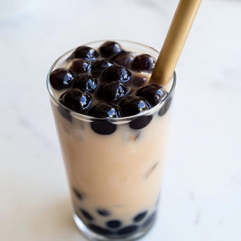 Creamy milk tea poured over ice and instant boba pearls in a tall glass, highlighting the Boba Tea Hack – Instant Bubble Tea with Sweetened Condensed Milk.