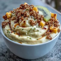 Vibrant mango chili lime smoothie bowl topped with fresh kiwi, granola, and coconut for a refreshing breakfast treat.