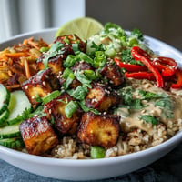 Golden baked tofu bowls piled high with fresh vegetables and creamy peanut sauce.